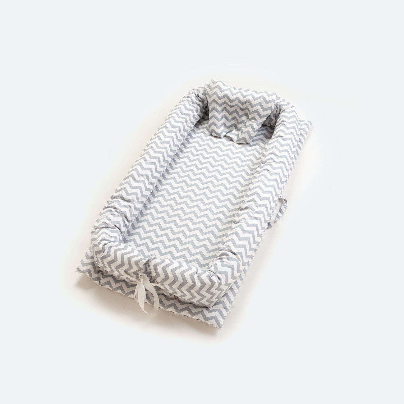 Portable cotton baby nest with gray chevron pattern, head support, and ties.