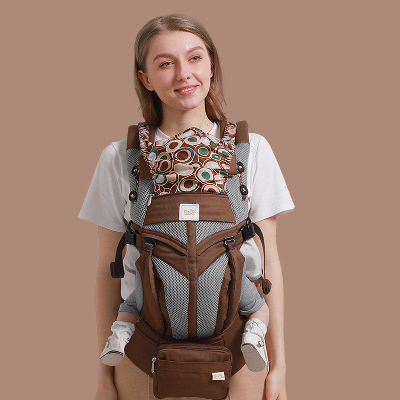 Woman smiling, wearing a brown and gray ergonomic cotton baby carrier with a patterned insert.