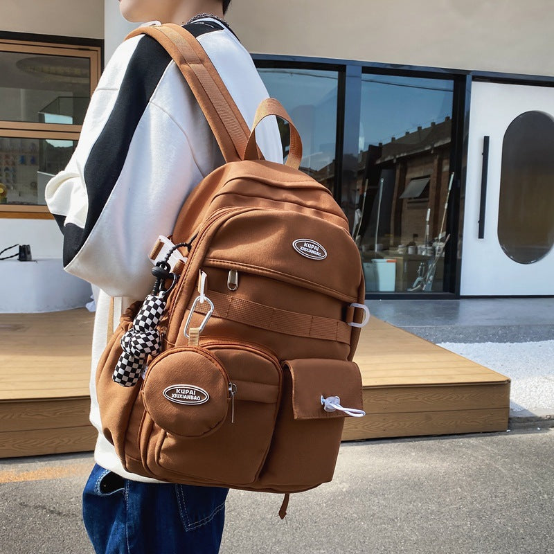 Brown nylon student backpack with laptop compartment, multiple pockets, and checkerboard charm.