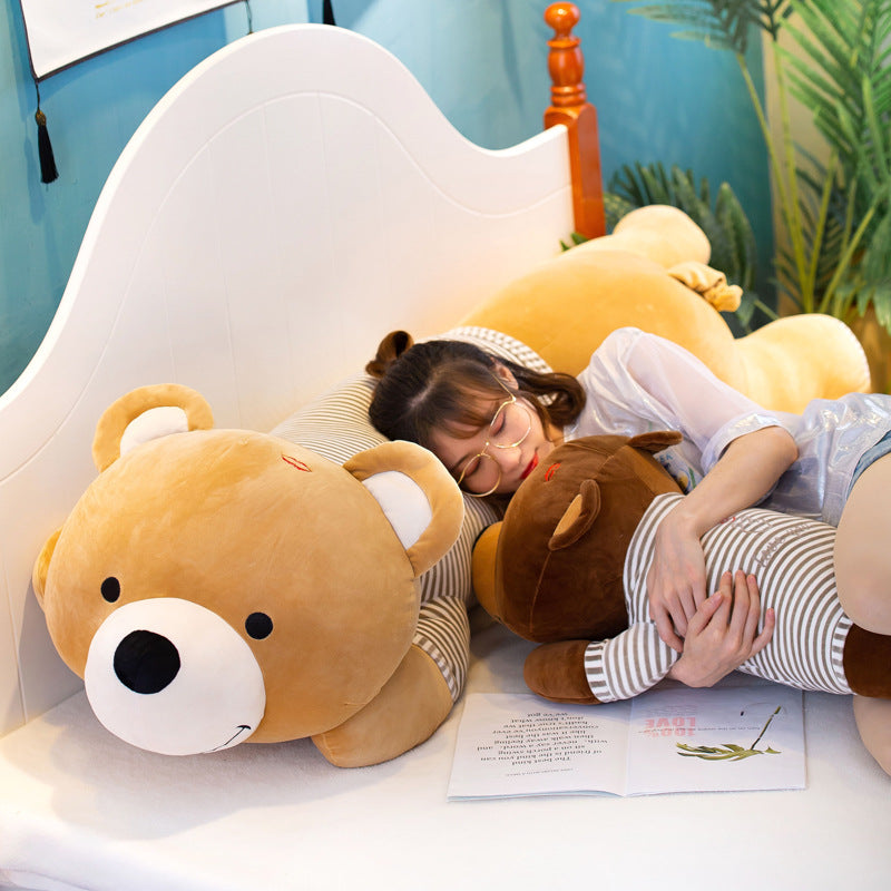 Soft brown plush lying teddy bear, 60cm, with a striped body, next to a person sleeping.