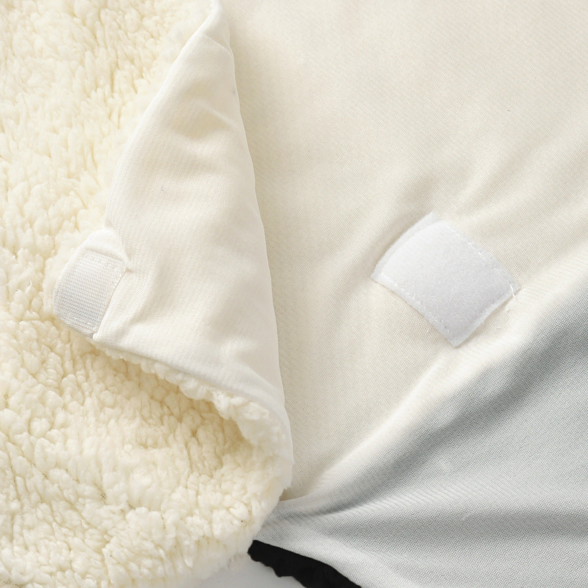 Soft cream fleece baby swaddle blanket with white velcro closures.