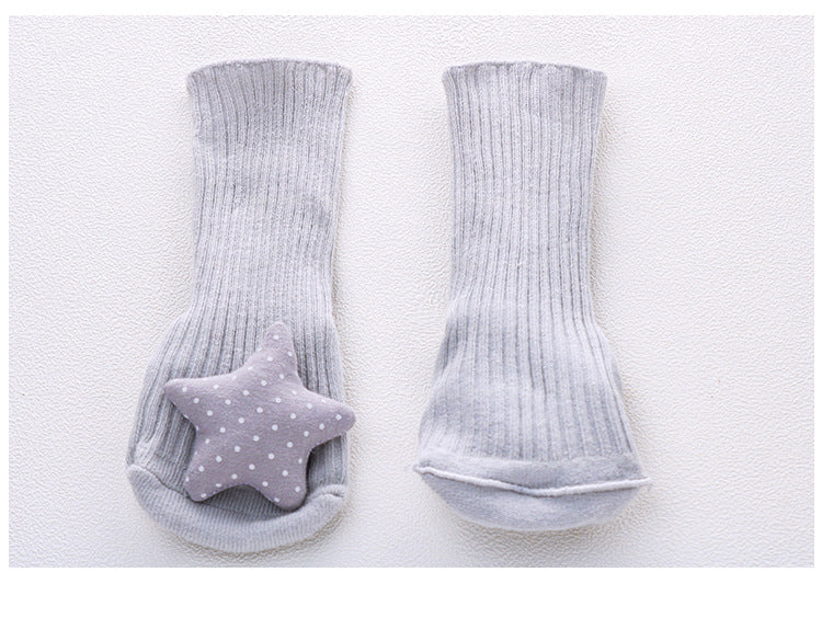 Pair of gray ribbed cotton baby socks with a polka-dotted star appliqué on one sock, featuring non-slip soles.