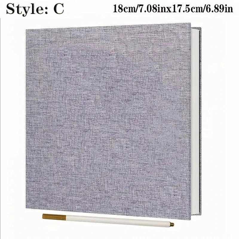 Light gray linen fabric photo album with spiral binding and a gold pen.
