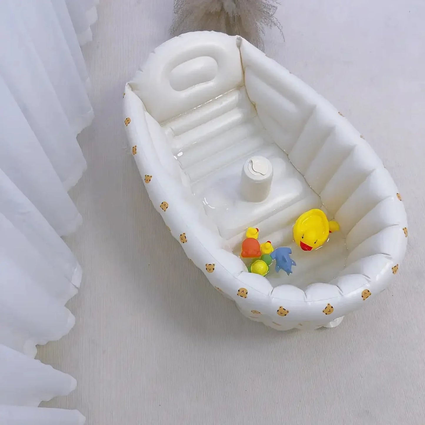 White inflatable baby bathtub with built-in pump, animal print, and bath toys.