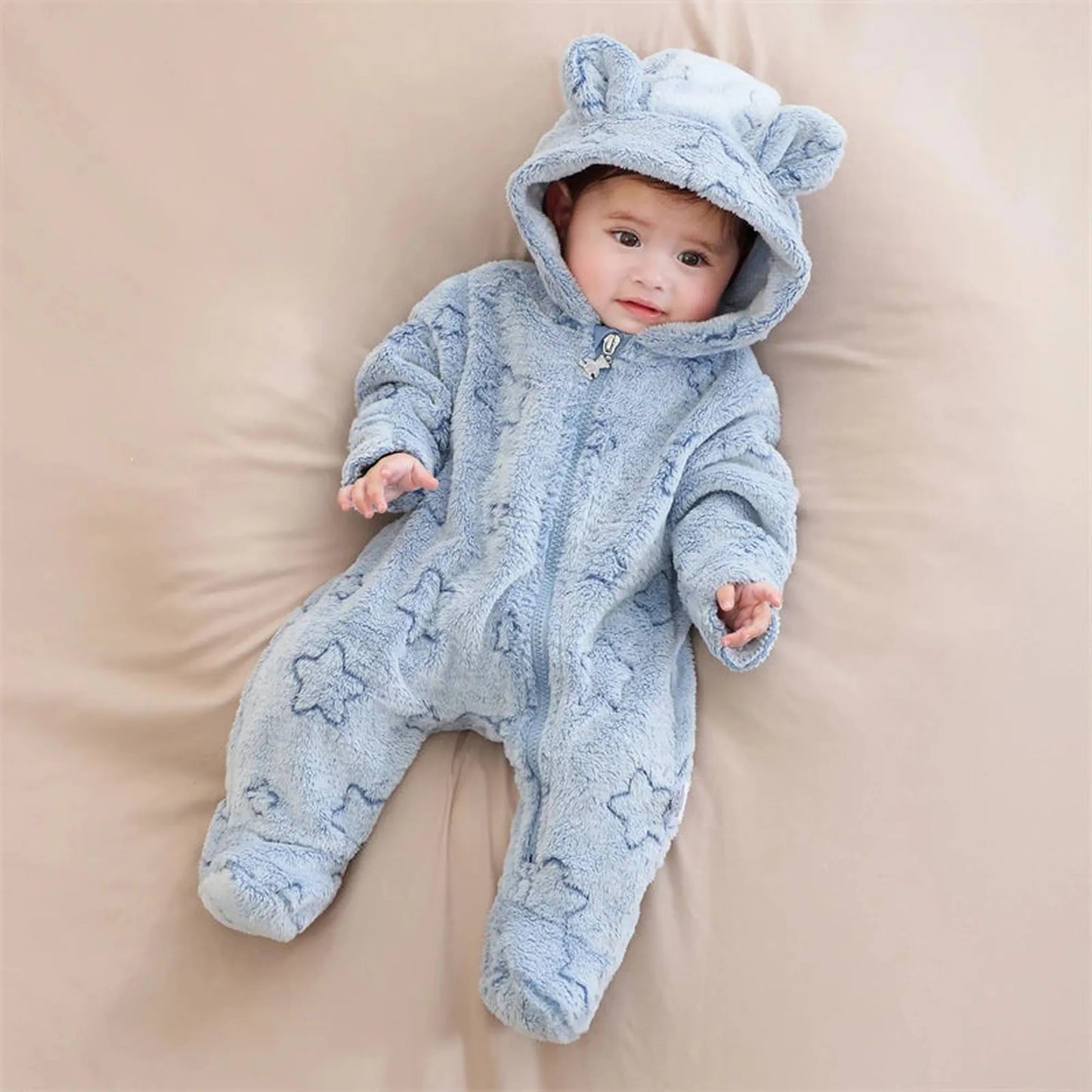 Baby in a cozy blue flannel romper with star patterns, a full zipper, and cute bear ears on the hood.