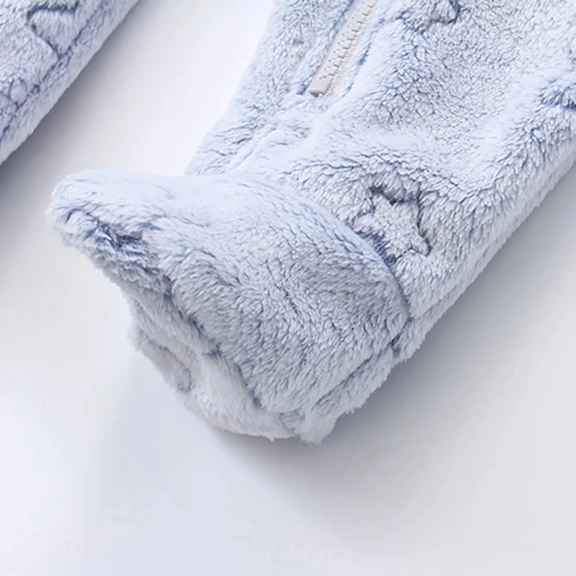 Close-up of a soft blue flannel baby romper with a zipper and footed design, featuring subtle star patterns.