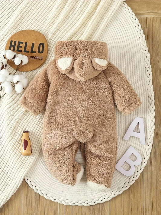Brown plush fleece baby romper with bear ears hood and tail, on a white knitted blanket.