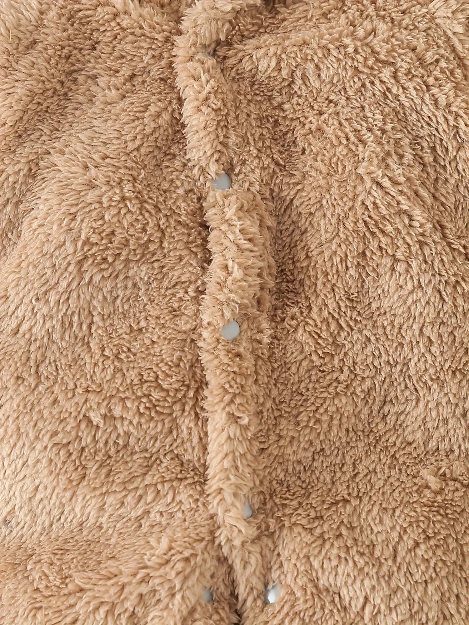 Close-up of a soft, fluffy beige fleece baby romper with snap buttons.