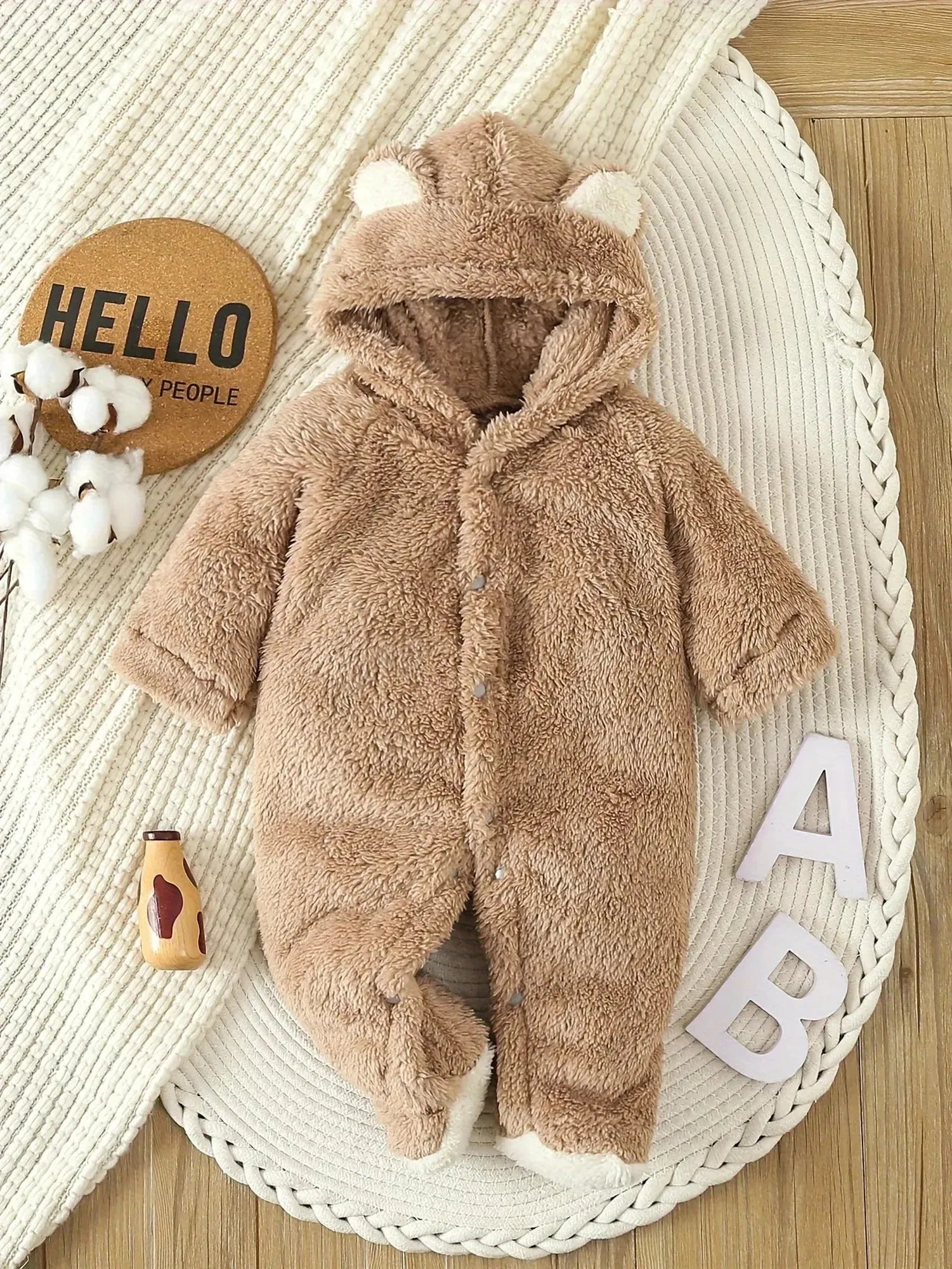 Warm brown fleece baby romper with bear ear hood, snap closure, and white trim.