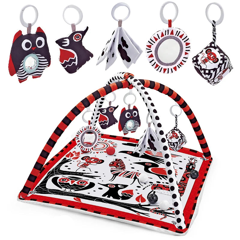 Red and black baby activity mat with arch, hanging owl toys, mirror, and soft ball.