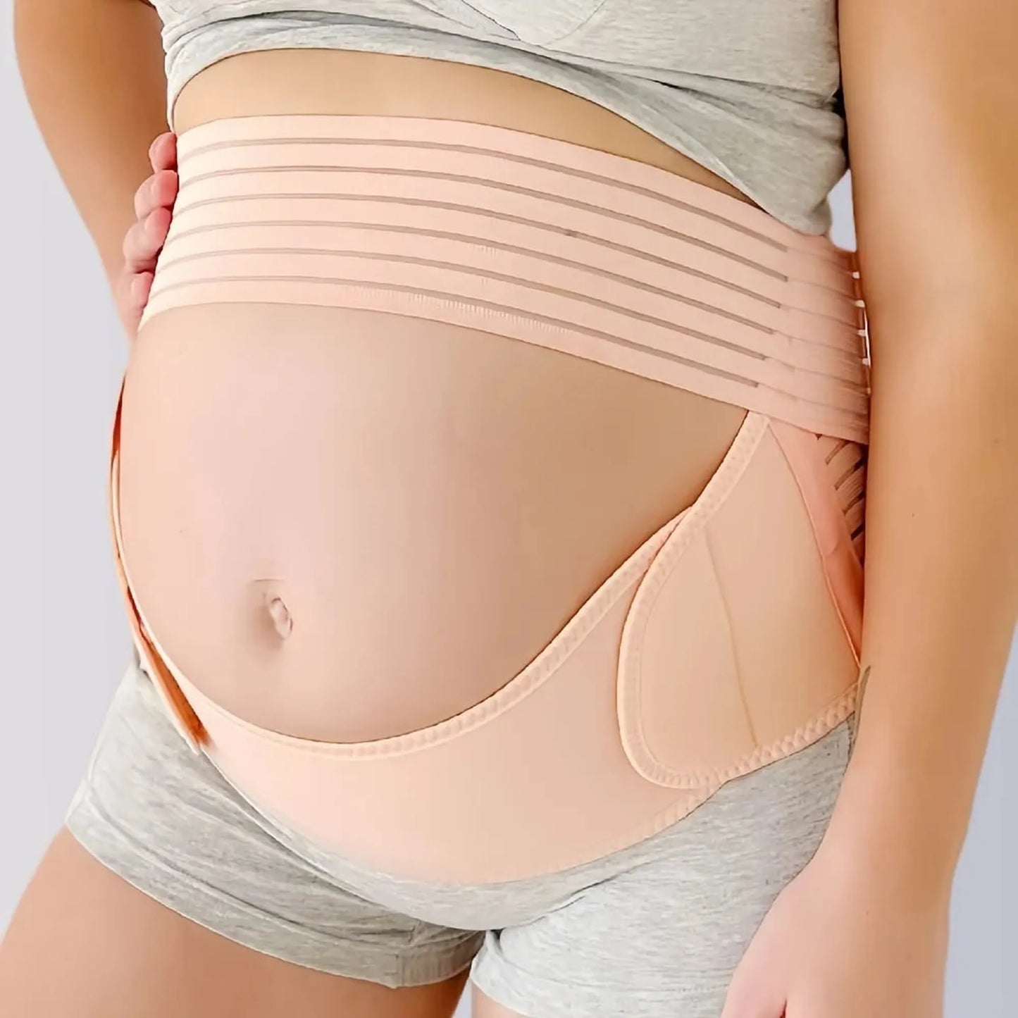 Adjustable peach maternity support belt on a pregnant belly, featuring breathable elastic fabric and a discreet design.