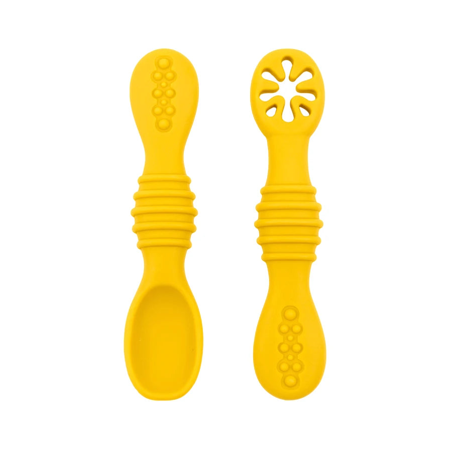 Two yellow silicone baby training spoons, one solid and one with a flower-shaped teether, for safe feeding.