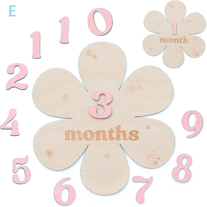 Wooden baby milestone cards with pink numbers and flower shapes.