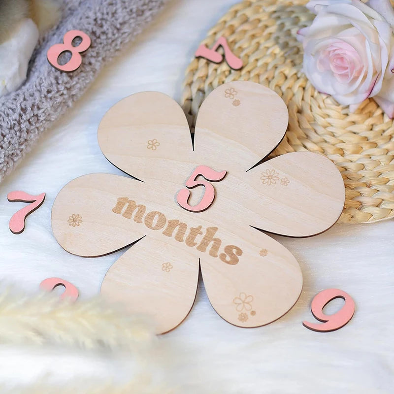 Wooden flower milestone card with "5 months" engraved, surrounded by pink number cutouts.