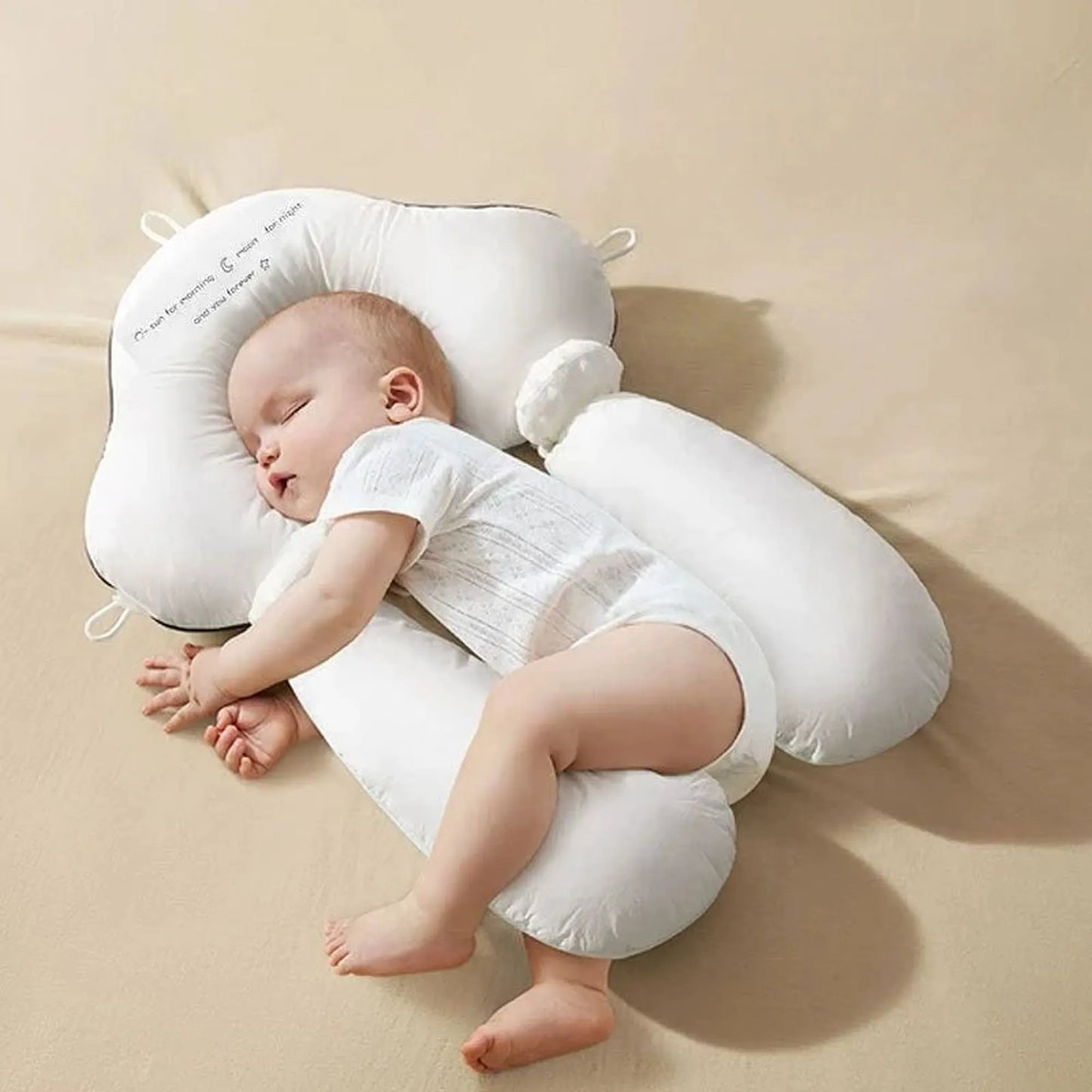 White ergonomic baby sleep pillow with side bolsters supporting a sleeping infant.