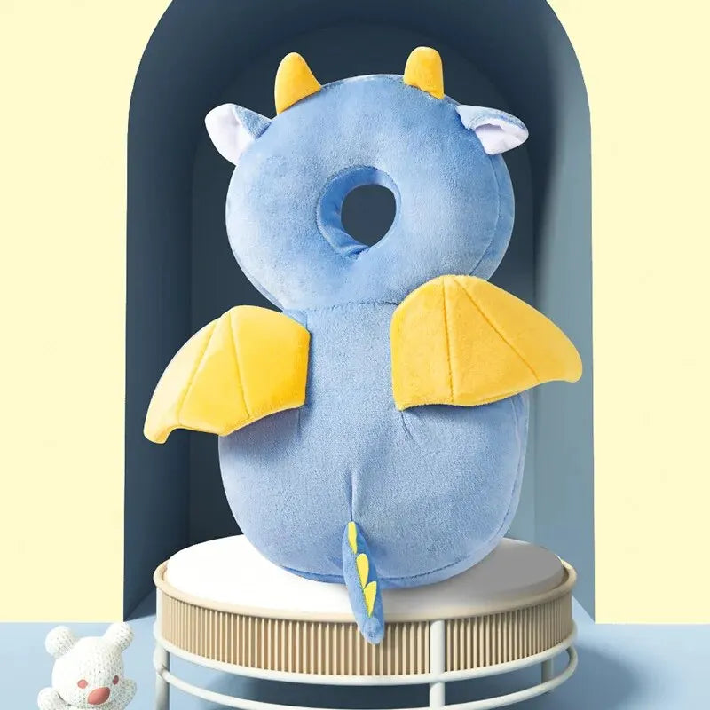 Blue baby head protection pillow with yellow dragon wings, horns, and tail, made of soft, breathable cotton.