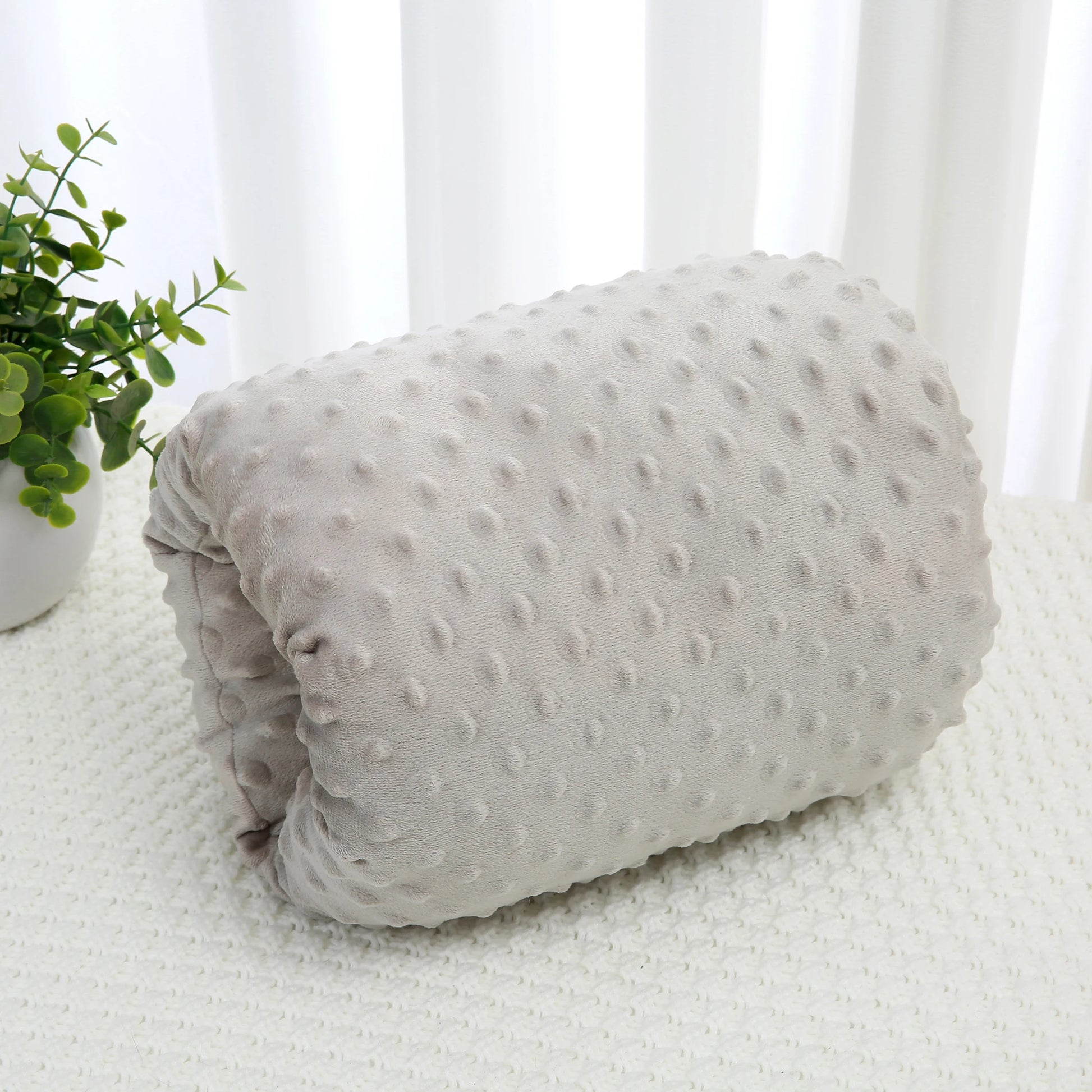 Soft gray nursing arm pillow with textured polka dots for comfortable baby feeding.
