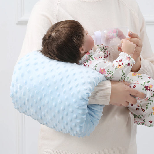 Light blue soft minky nursing arm pillow supporting a baby being bottle-fed by an adult.