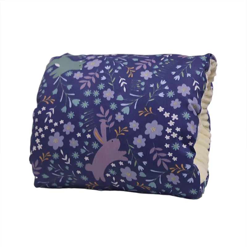Navy blue nursing pillow with a floral and bunny print, featuring a soft, textured cream underside.