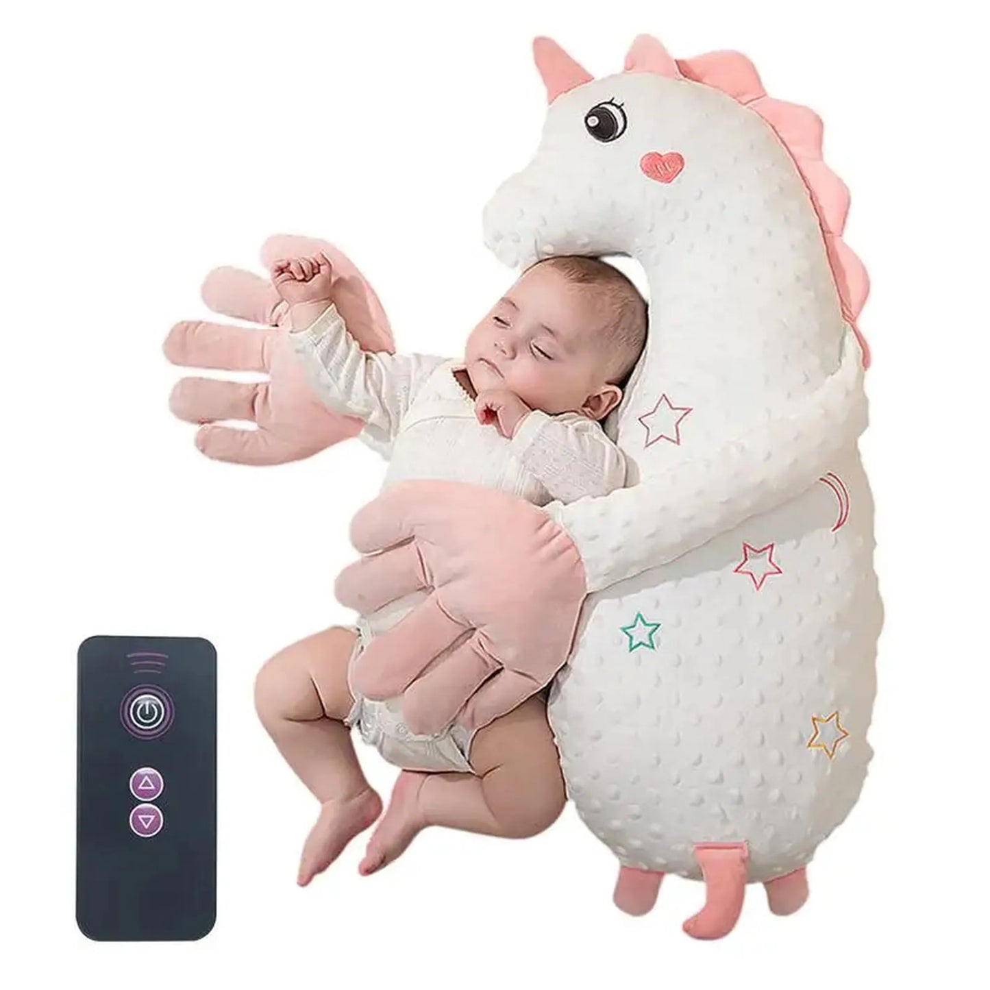 Baby sleeping soundly in a white unicorn electric soothing pillow with pink hands, beside a black remote.