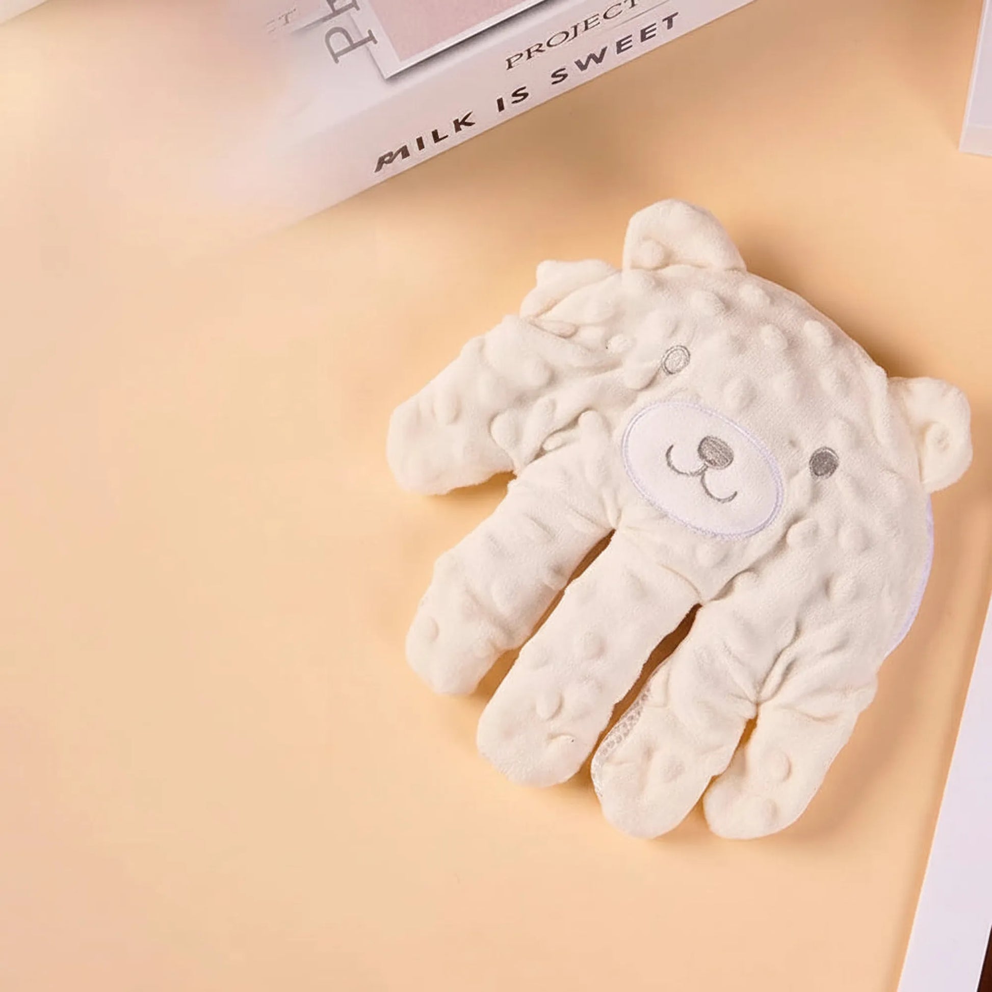Creamy white bear-shaped baby soothing pillow with gentle patting function, soft cotton material.