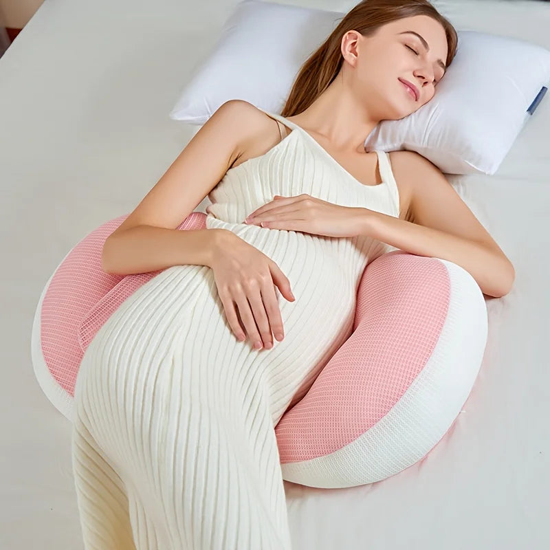 Pregnant woman sleeping peacefully with a pink and white U-shaped maternity pillow for full body support.