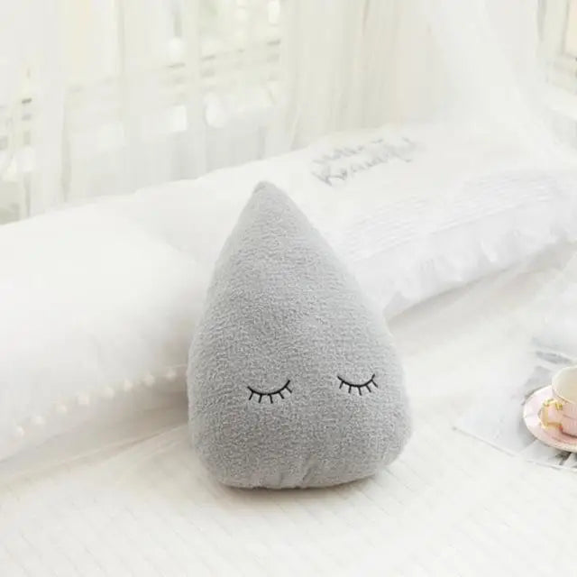 Soft gray teardrop-shaped decorative pillow with embroidered sleeping eyes, ideal for nursery decor.