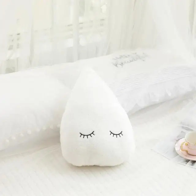 Soft white plush teardrop pillow with embroidered closed eyes, perfect for nursery decor.