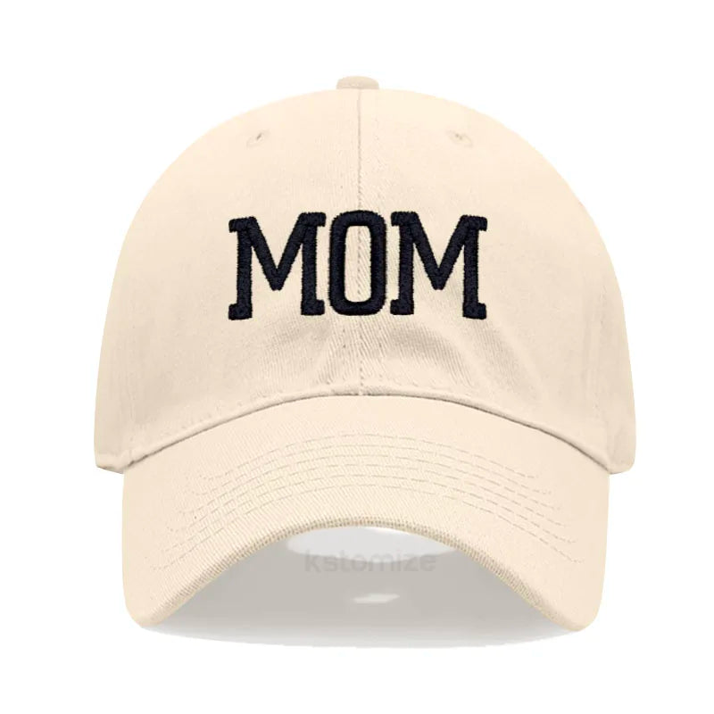 Adjustable beige cotton baseball cap with "MOM" embroidered in dark blue letters.