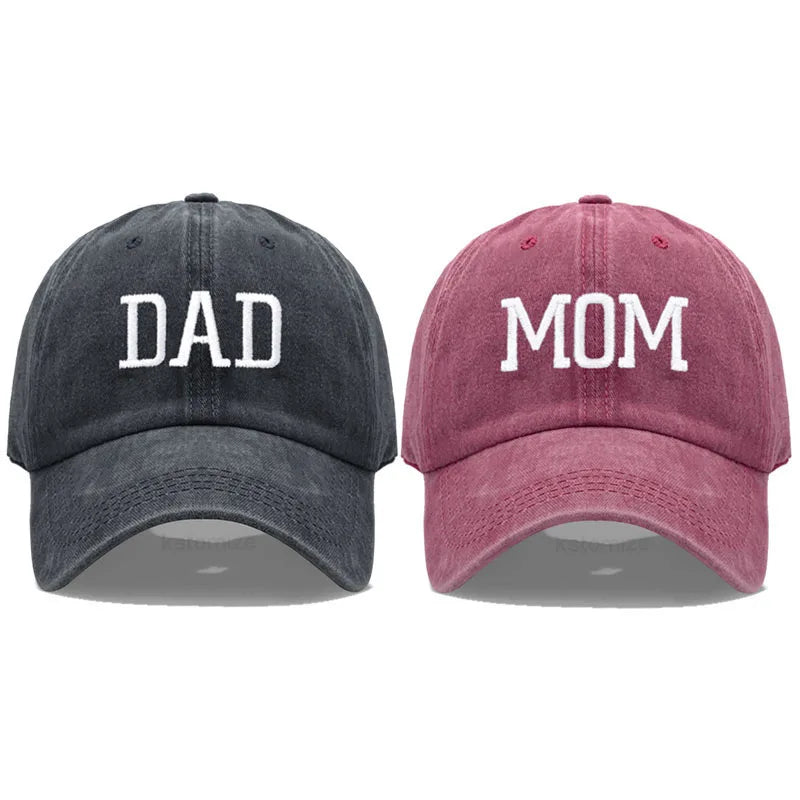 Adjustable cotton baseball caps: charcoal "DAD" and maroon "MOM" with white embroidered letters.