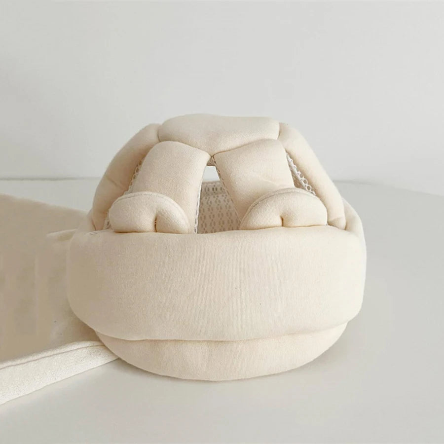 Breathable beige toddler head protection helmet with soft padding and mesh ventilation.