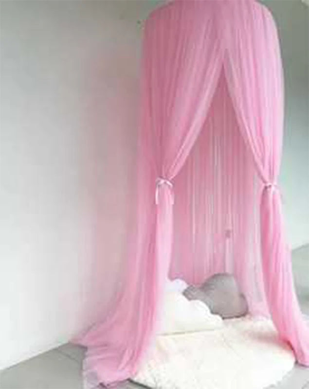 Pink sheer polyester canopy for a baby crib, tied back with bows, over a white rug.