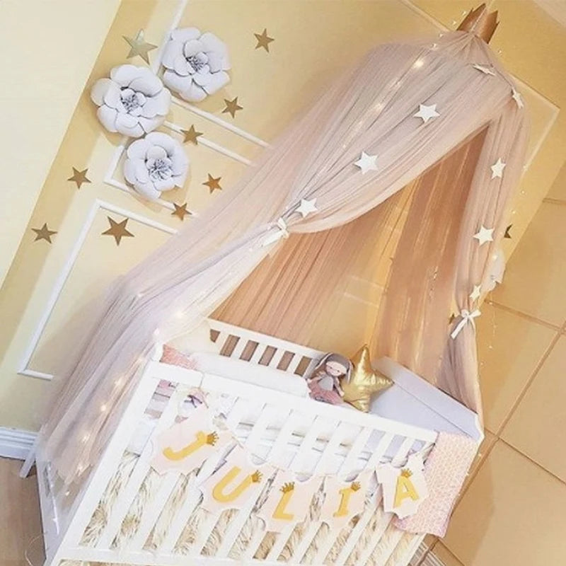 Pink tulle baby crib canopy with white stars and a gold crown, creating a dreamy nursery.