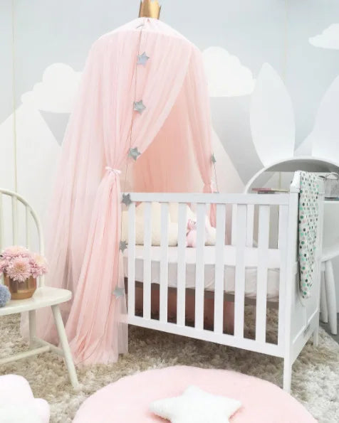 Pink tulle baby crib canopy with star decorations and a gold crown top.