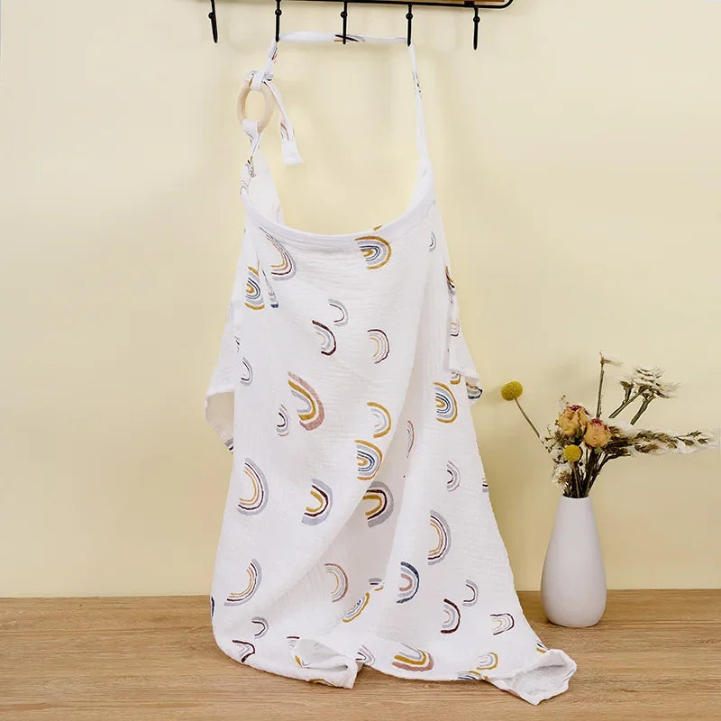 White cotton nursing cover with colorful rainbow print and wooden ring.