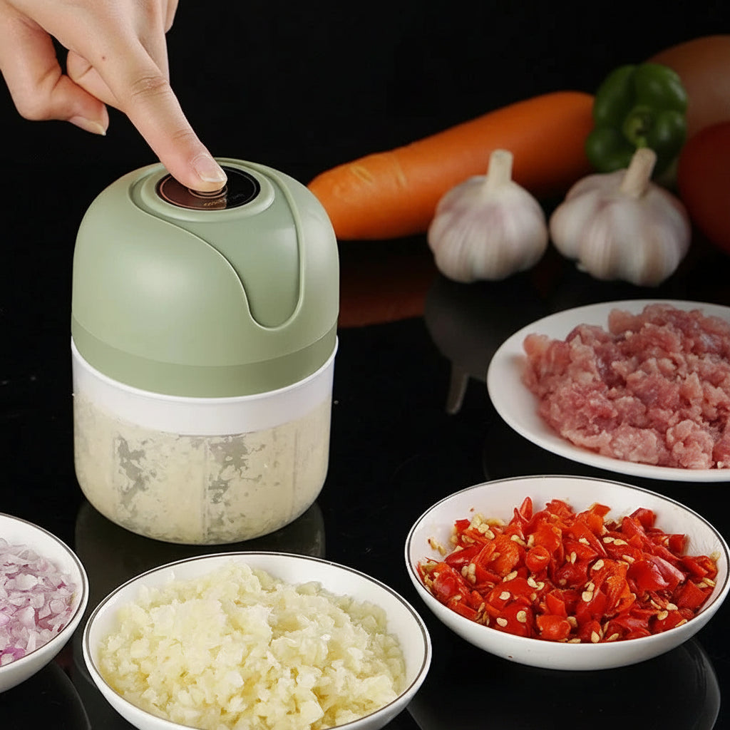 Green and white mini electric food processor with chopped garlic, onions, and peppers.