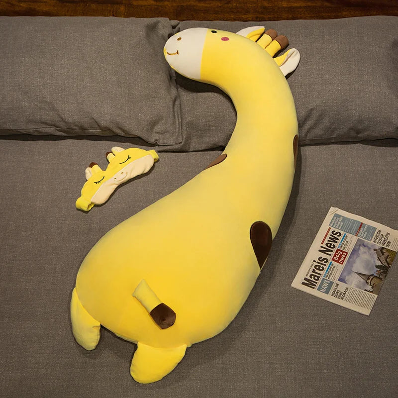 Soft yellow giraffe plush pillow and small matching headrest on a gray bed.