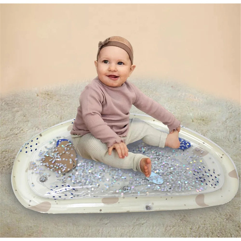 Happy baby sitting on an inflatable water play mat with floating glitter and colorful shapes.