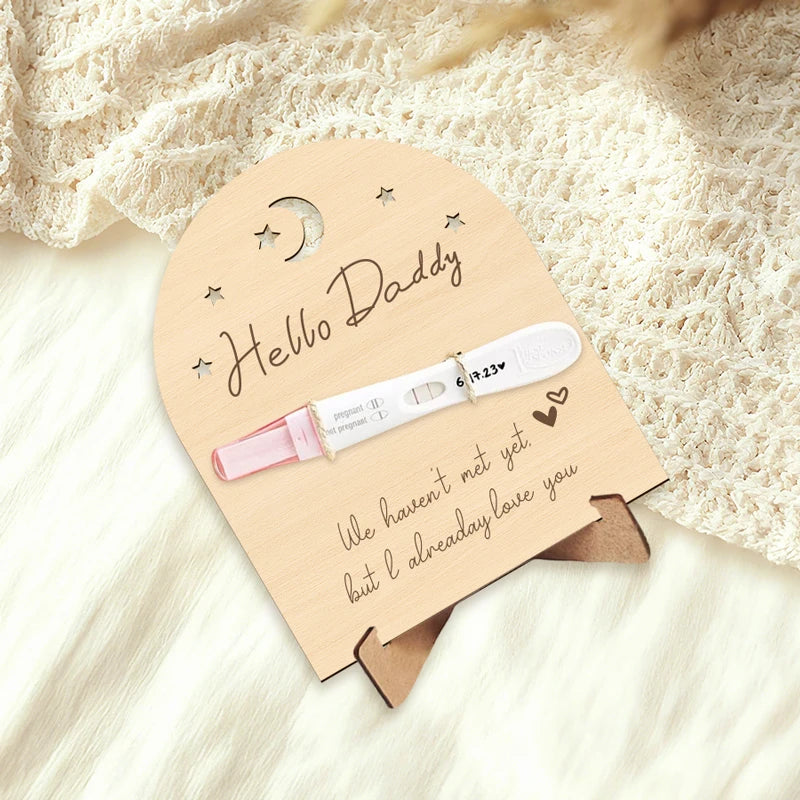 Wooden "Hello Daddy" pregnancy announcement sign with a positive test, moon, and stars.