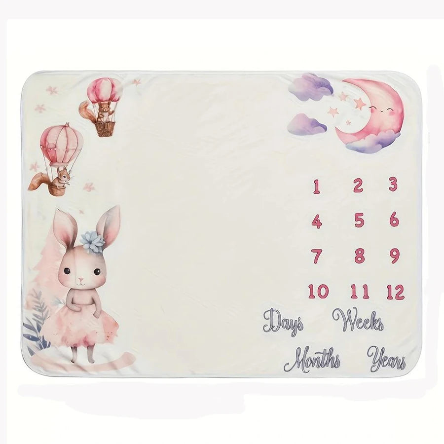 Soft white baby milestone blanket with pink bunny, hot air balloons, moon, stars, and numbers 1-12.