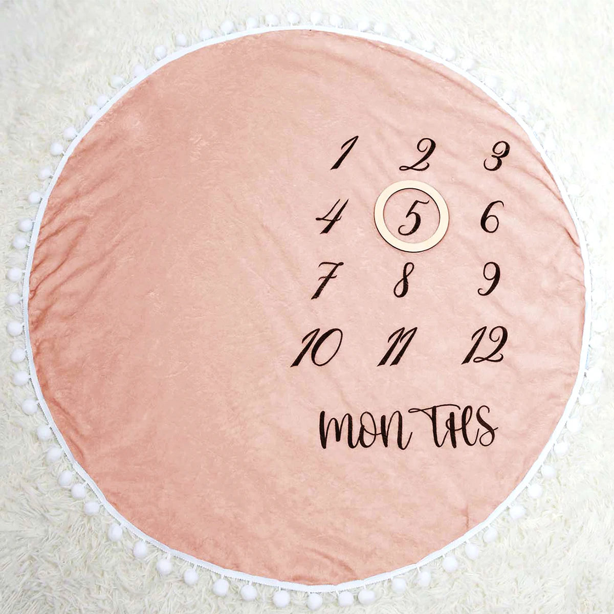 Pink flannel baby milestone blanket with white pom-pom trim and numbers 1-12 for monthly photos.