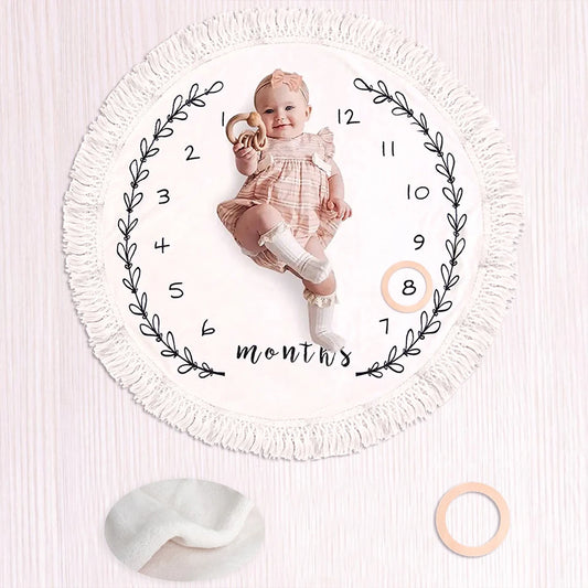 Baby milestone blanket, round 100x100cm, with monthly numbers, fringe, and a baby.