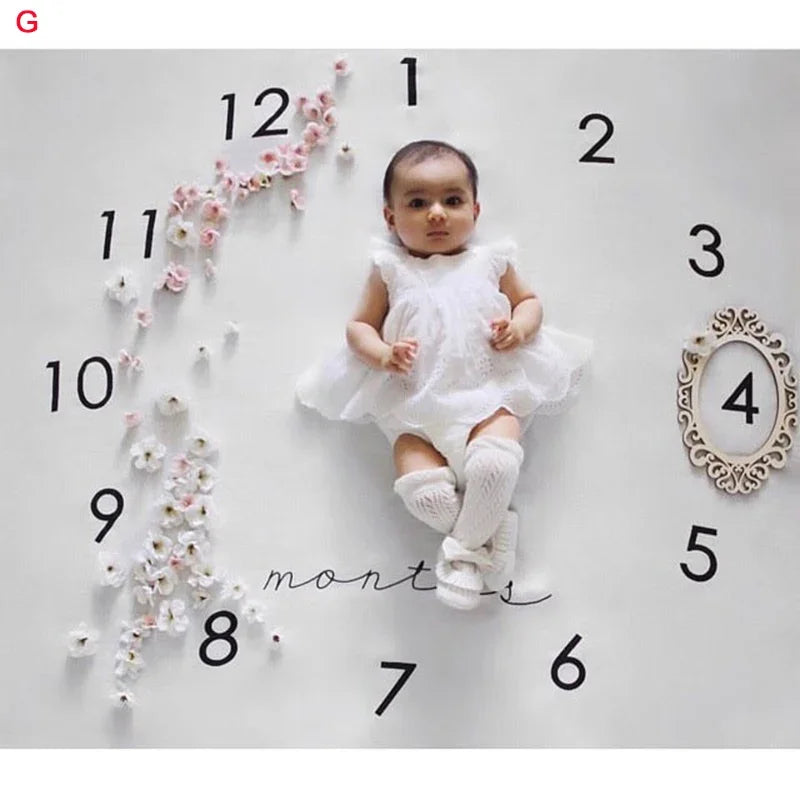 White polyester baby milestone blanket with clock design, floral accents, and a baby.