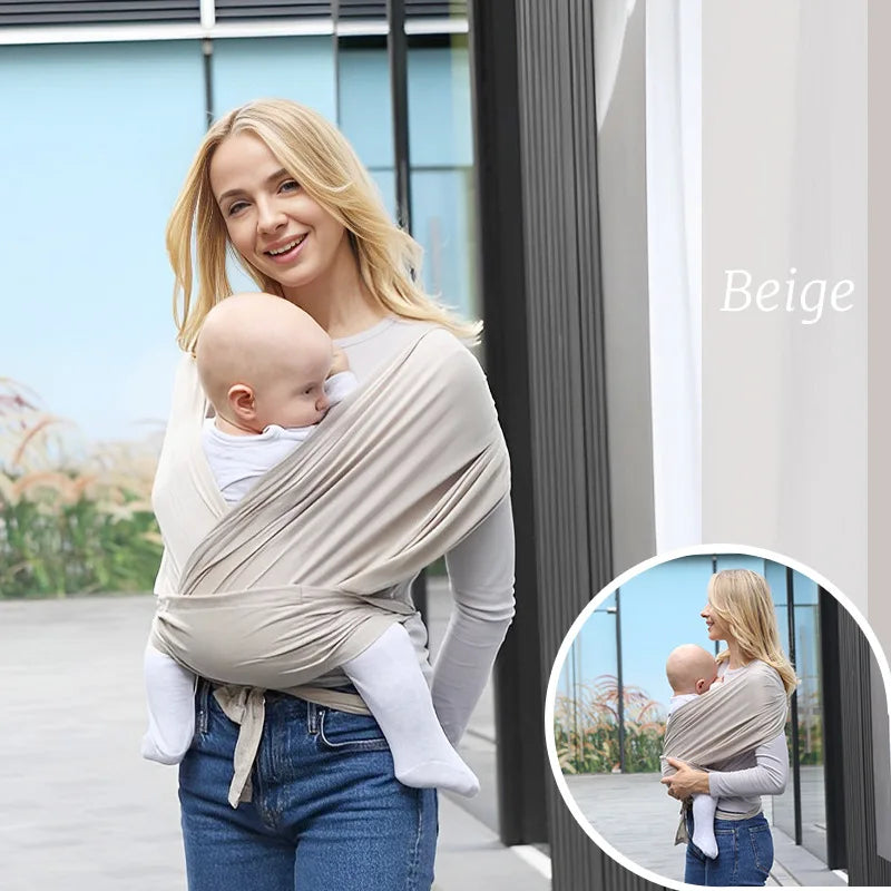 Smiling woman wearing a beige ergonomic cotton baby wrap carrier with a baby.