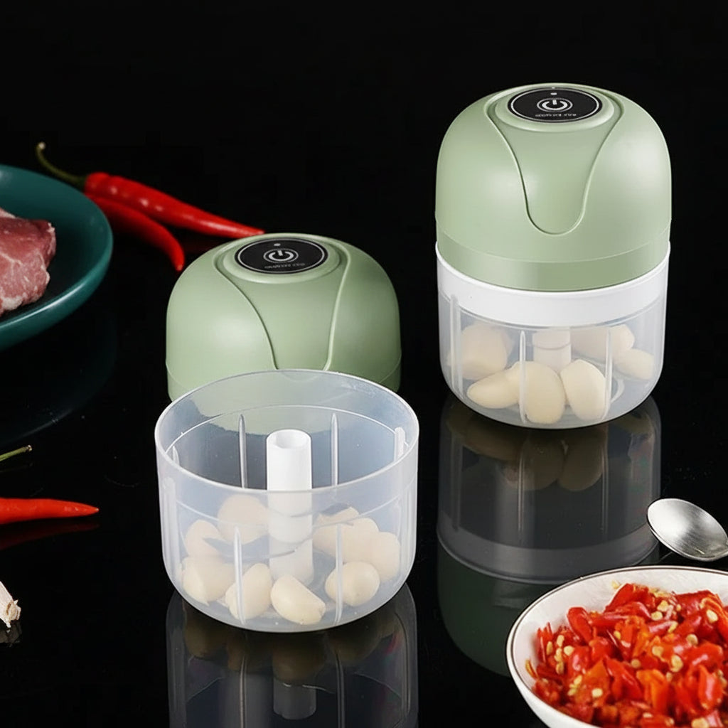 Green and clear 250ml mini wireless electric food chopper with garlic, next to its clear base.