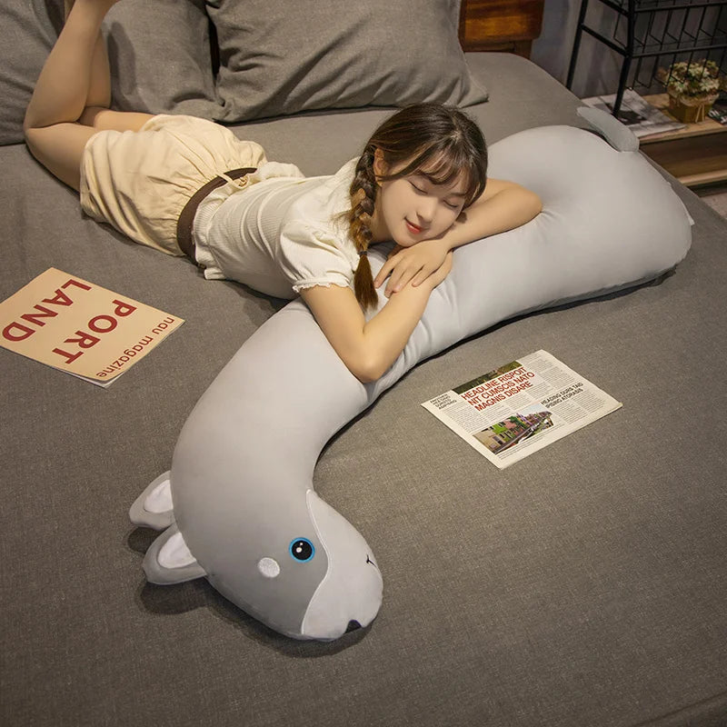 Soft gray dolphin plush body pillow with a girl resting on it in a bedroom.