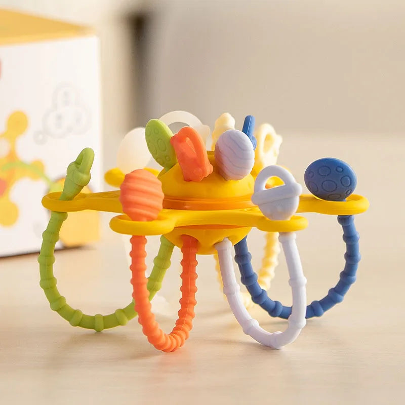 Montessori silicone sensory pull string toy with yellow center, colorful textured strings, and pop-it bubbles.