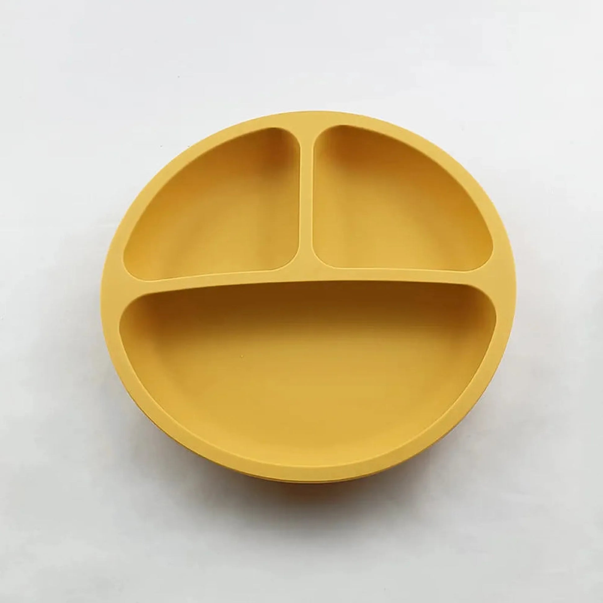 Mustard yellow silicone suction plate for self-feeding, with three divided sections for toddlers.