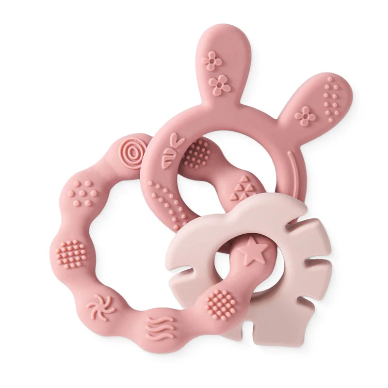 Pink silicone bunny and flower baby teethers with textured surfaces.