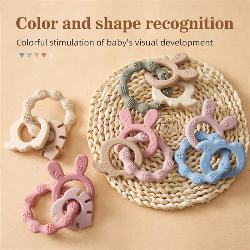 Assorted silicone bunny teethers in pastel pink, blue, beige, and gray with textured rings.
